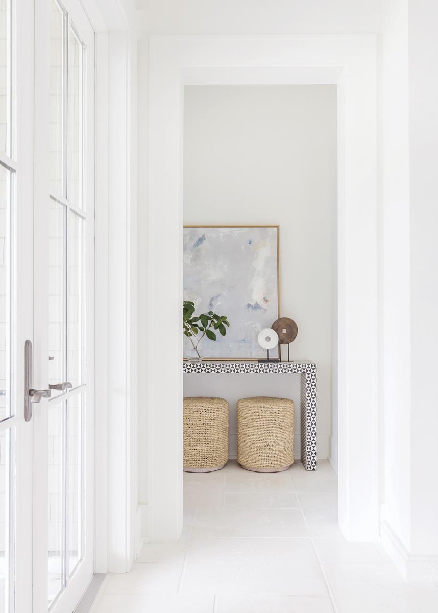 A geometric console and raffia poufs strike the ideal balance of design sentiments at the entry to the primary bedroom