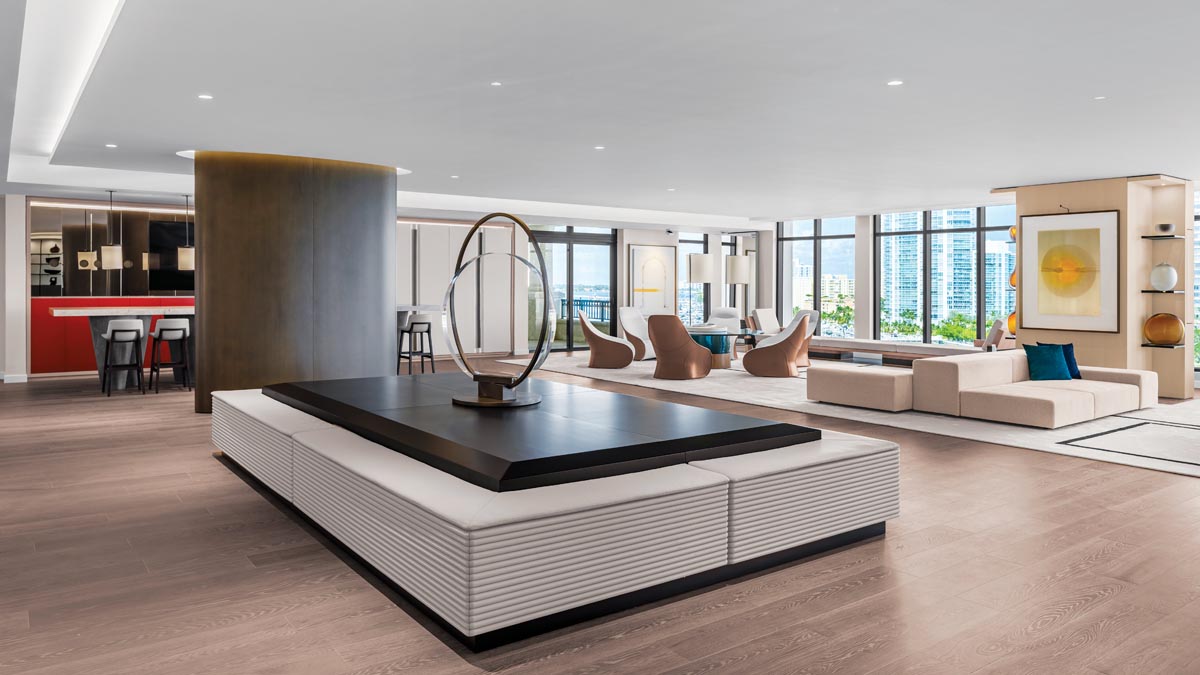 Upon entering the spacious quarters of this extraordinary Fisher Island penthouse, a larger-than-life ottoman surrounding a 42-inch optical glass artwork lends a strong sculptural statement to the adjacent open living spaces. Designed by Poggi Design, the majestic piece preludes the sweeping Biscayne Bay views beyond.