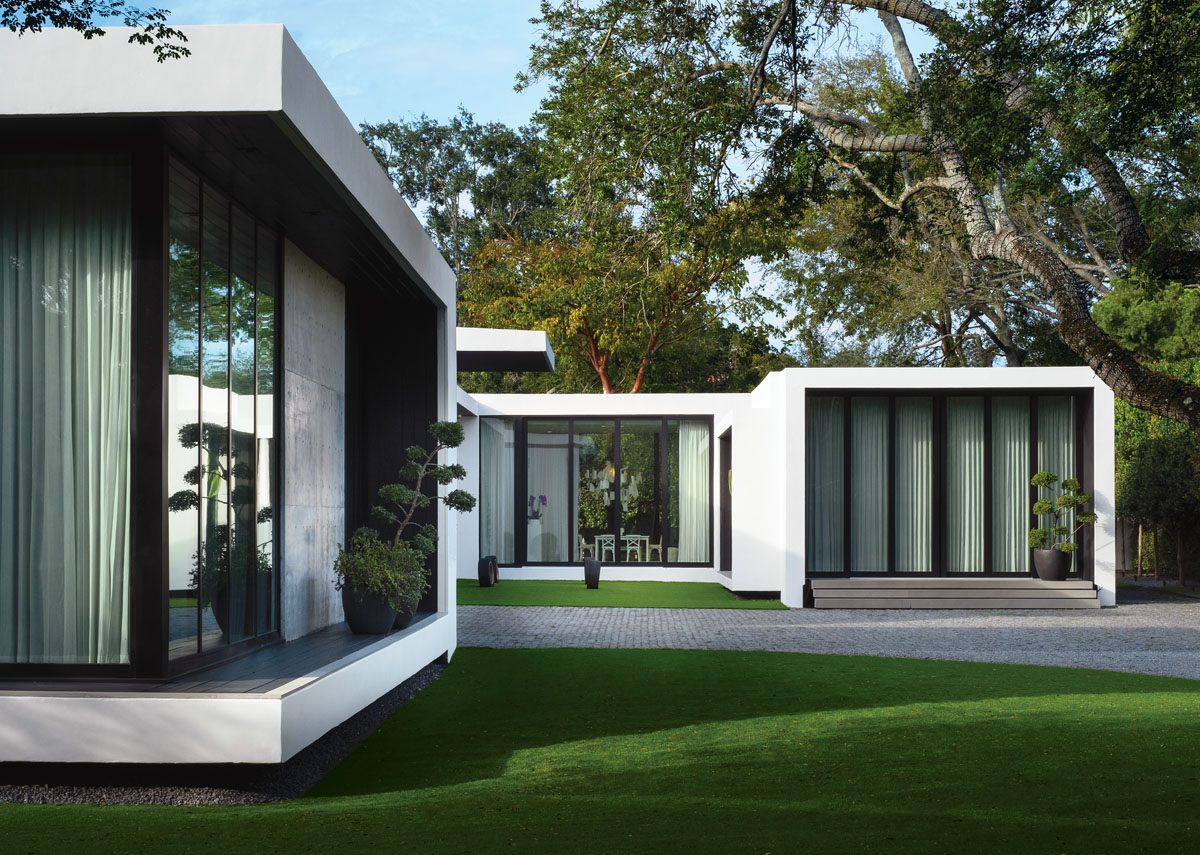 Graceful live oaks frame the geometric lines of this “tropical modern” home. Concrete slabs step up to Alex’s private office that is seamlessly connected to the home via glass sliders that open to a central courtyard.