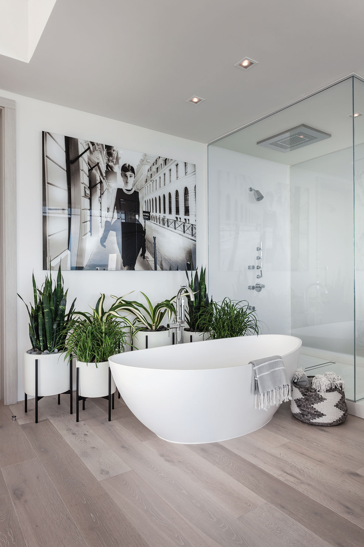 A large black-and-white photograph of Audrey Hepburn by photographer Axel Crieger keeps watch in the master bath over a vessel tub, a "rain" shower and a collection of lush plants.