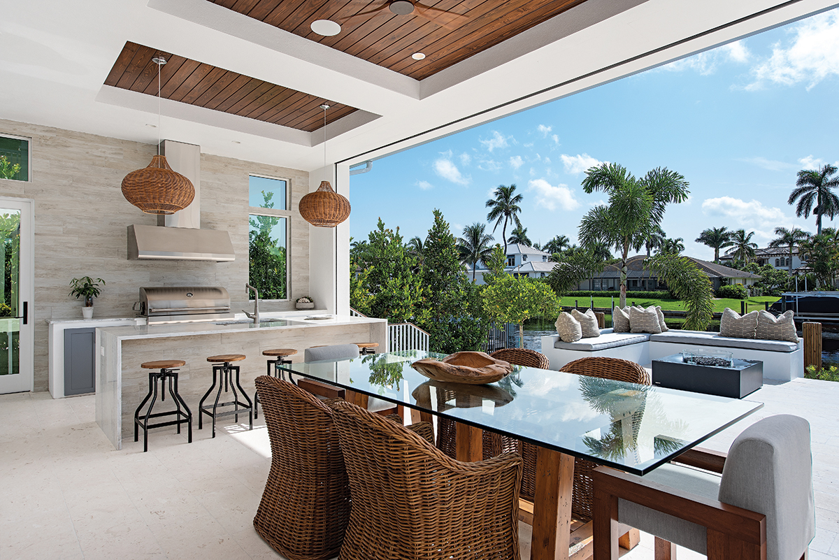 On the loggia, guests enjoy midday bites seated at the Ralph Lauren dining table or early evening cocktails on industrial style stools that pull up to the outdoor kitchen island nearby. A set of wicker pendants from Kouboo — custom stained to match the wood ceiling — cast circles of light from above.