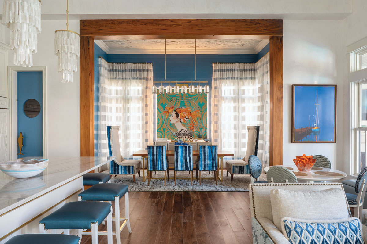 Awash in tranquil shades of blue, the dining room chairs are backed with an undulating Viridis Topaz ombre-stripe velvet. Ashley Longshore’s fishbowl painting provides an eye-grabbing focal point, and linear crystal lighting floats overhead like a sparkling crown.