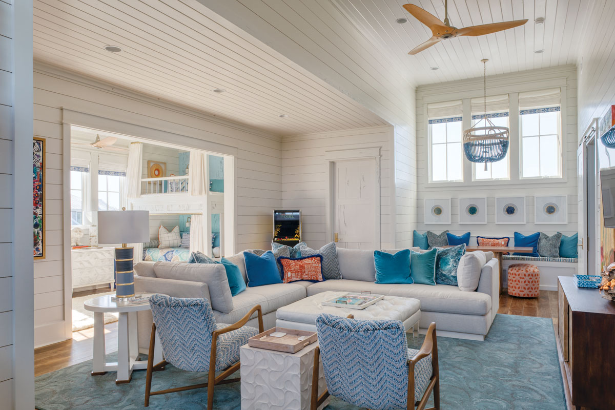 The third-floor game room is all about family fun, featuring a plush sectional, a tufted ottoman, and a long window seat with a game table where the homeowners’ six grandchildren color, craft, snack, and play.