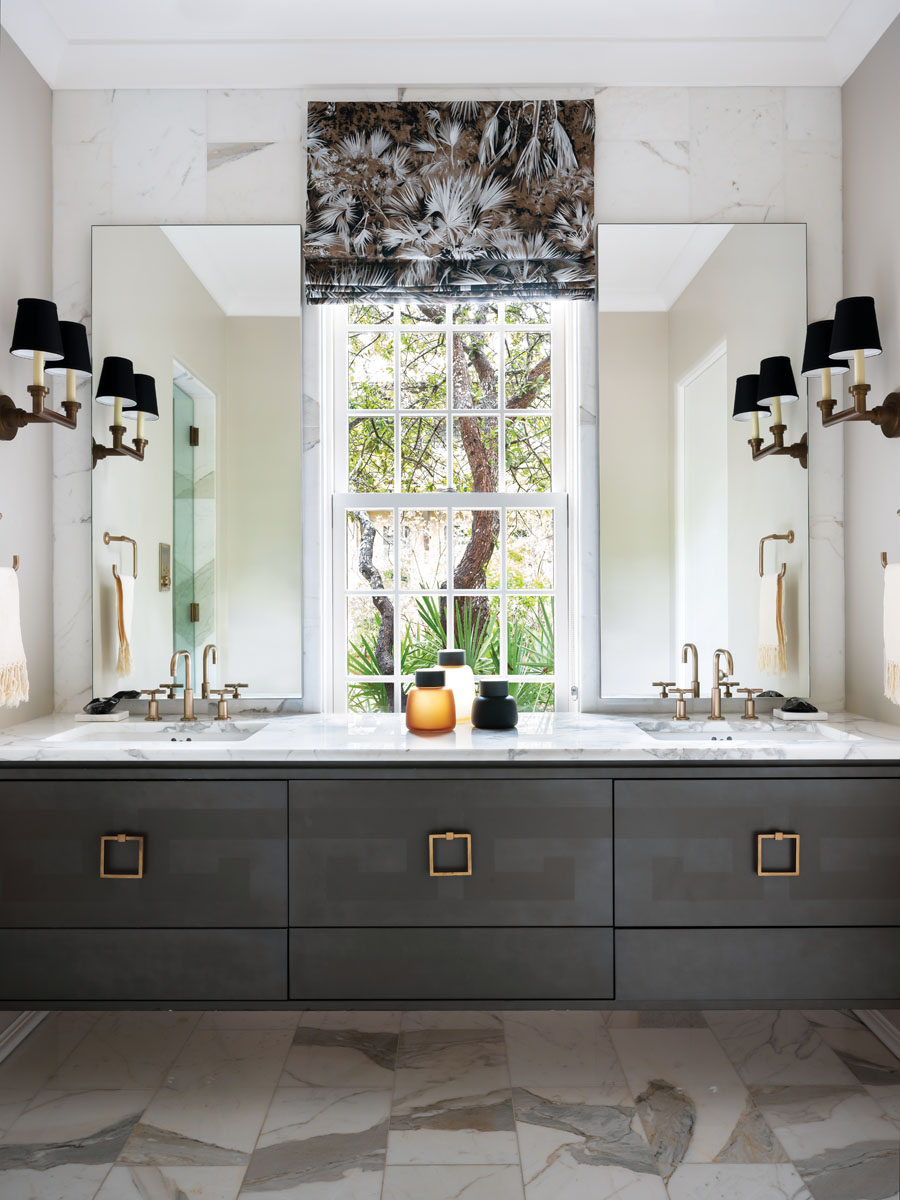 The light-filled master bathroom looks out over the home’s lush front yard. Floating dual vanities in a heavy wood grain are anchored by Kohler fixtures.