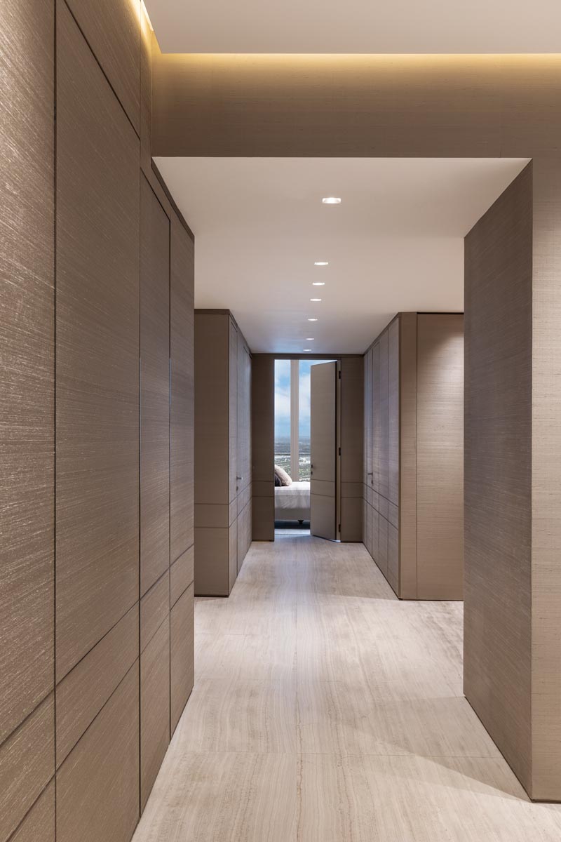 Paving the hallway to the primary bedroom, book-matched Vena Grigio marble flooring mirrors Armani’s original design for the building’s lobby. Custom wall paneling covered in Phillip Jeffries silk wallpaper elevates the minimalist aesthetic.