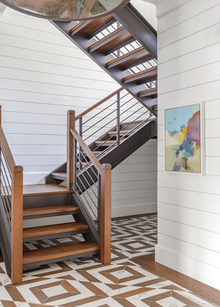 “We wanted the staircase in the foyer to look like it was floating,” Webster says. “To see through the treads and have it feel open and airy.” The mahogany wood in the staircase and newel posts were bleached and then stained with a bronze finish to complement the rich brown foyer floor accents.