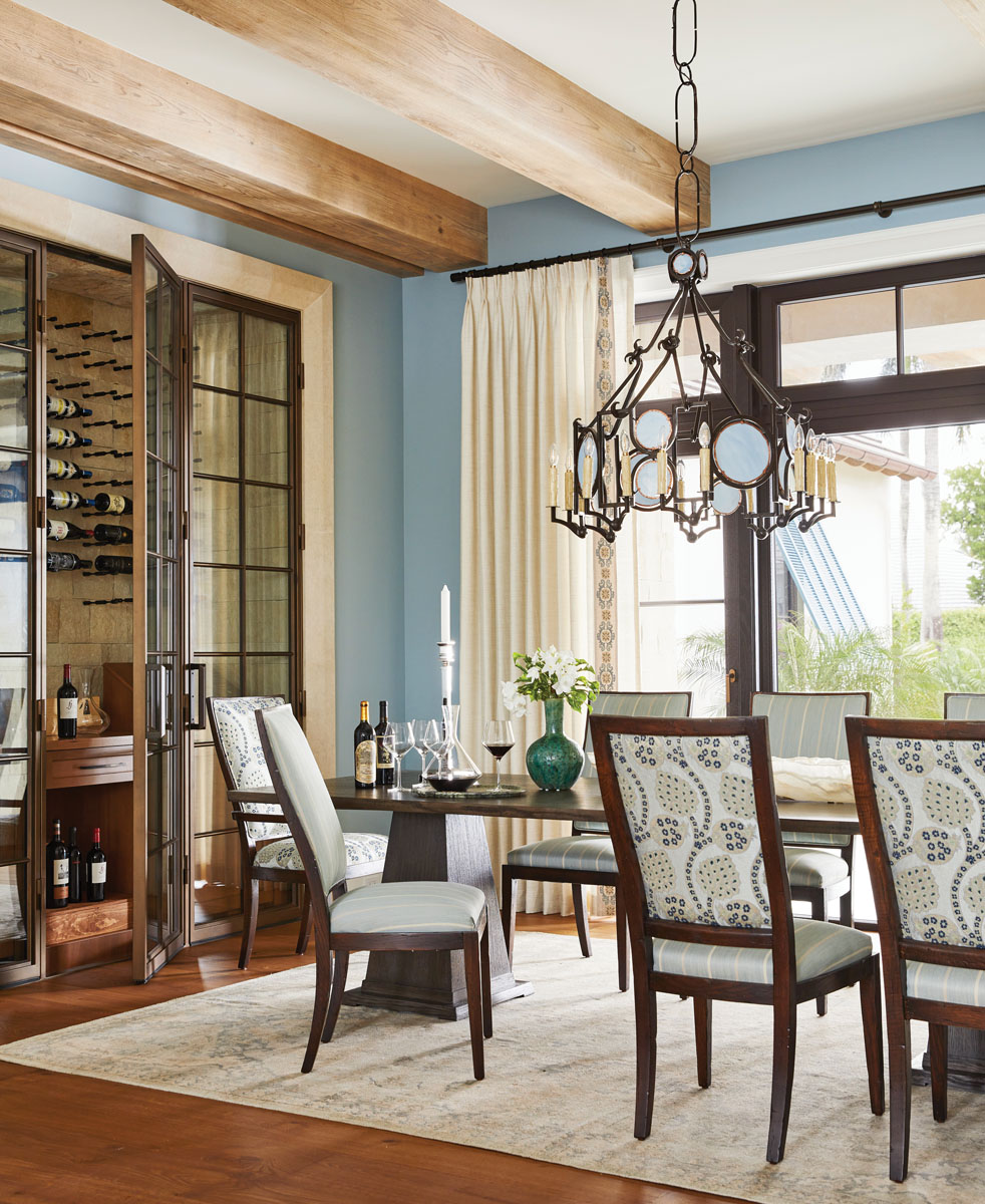 The stacked stone that surrounds the wine cabinet and weathered oak ceiling beams in the dining room echo the home’s exterior and add to its architectural integrity. The chandelier, from Los Angeles-based Richard Ray Custom Design, along with Chaddock dining chairs whimsically upholstered with both Thibaut and Schumacher fabrics in warm neutrals, make the dining room dynamic and interesting.