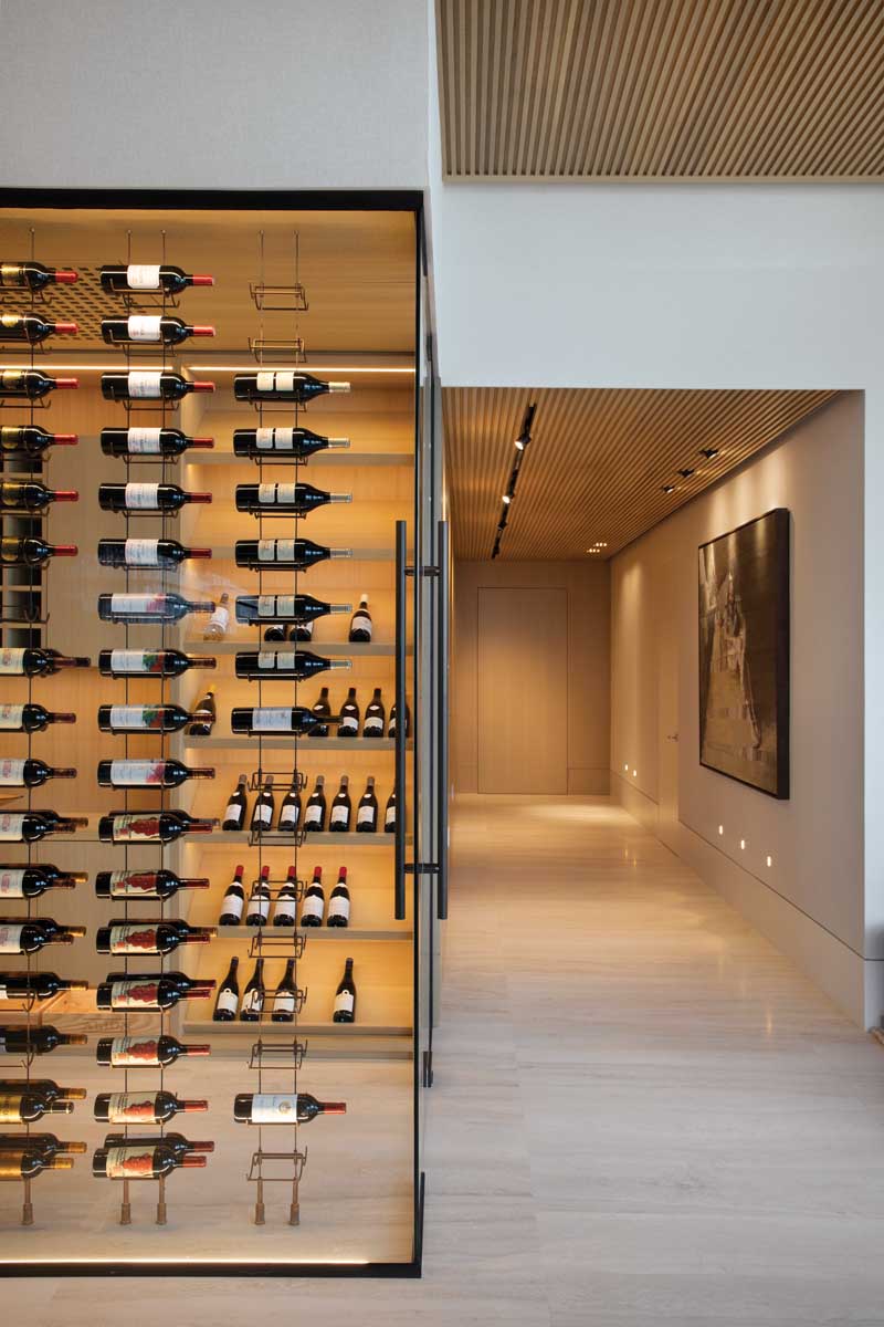 The all-glass wine cellar, built to accommodate more than 350 bottles, has a white oak floor-to-ceiling cabinet with LED-lit shelves and a floating cabinet with a Taj Mahal quartzite recessed counter.