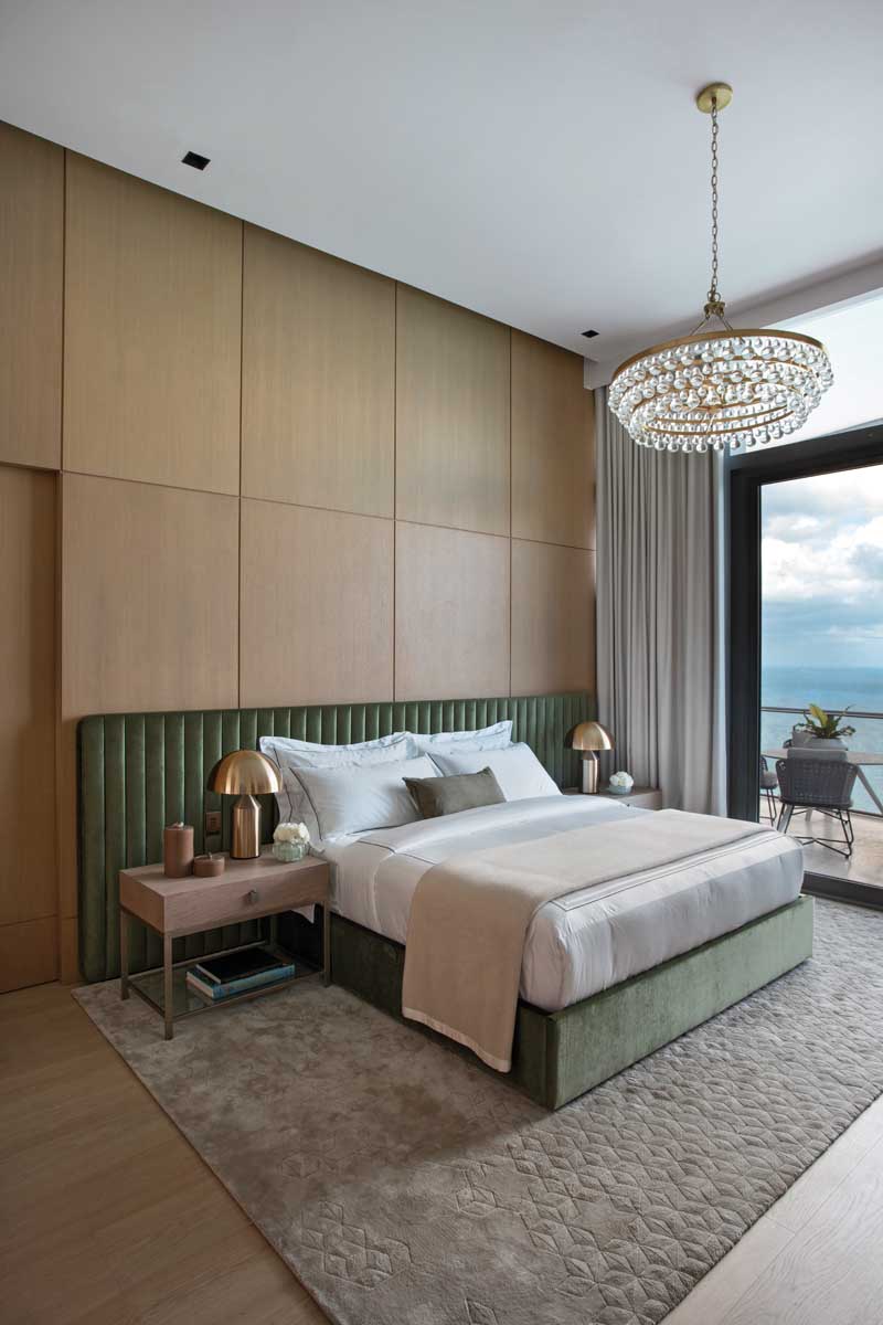 In the primary bedroom, Jaegger chose an emerald green shade for the custom velvet headboard fabricated by Casa Dio. Highlighting the custom-designed white oak wall panels are a Bling chandelier by Robert Abbey and a Star Silk rug by Helen Amy Murray for The Rug Company.