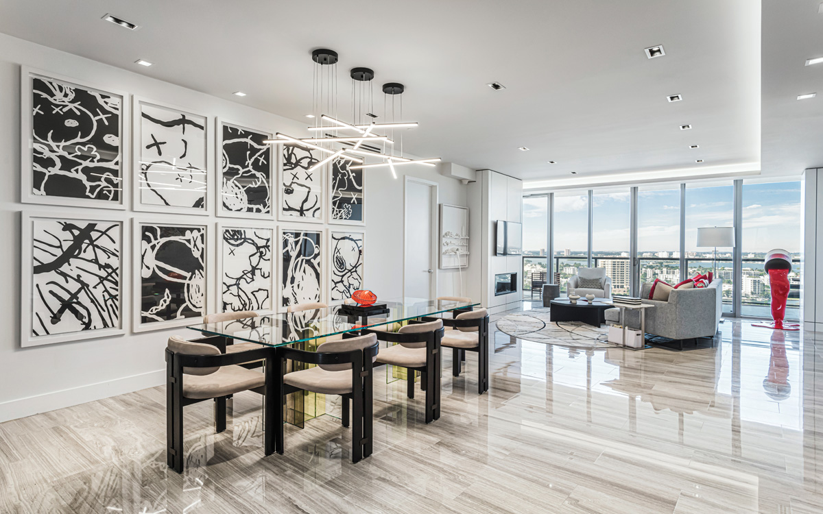 A view of the dining room reveals a set of Kaws drawings and a dining table from Roche Bobois. In the family room, which offers views of the Intracoastal Waterway, a fireplace and TV set were integrated into the wall.