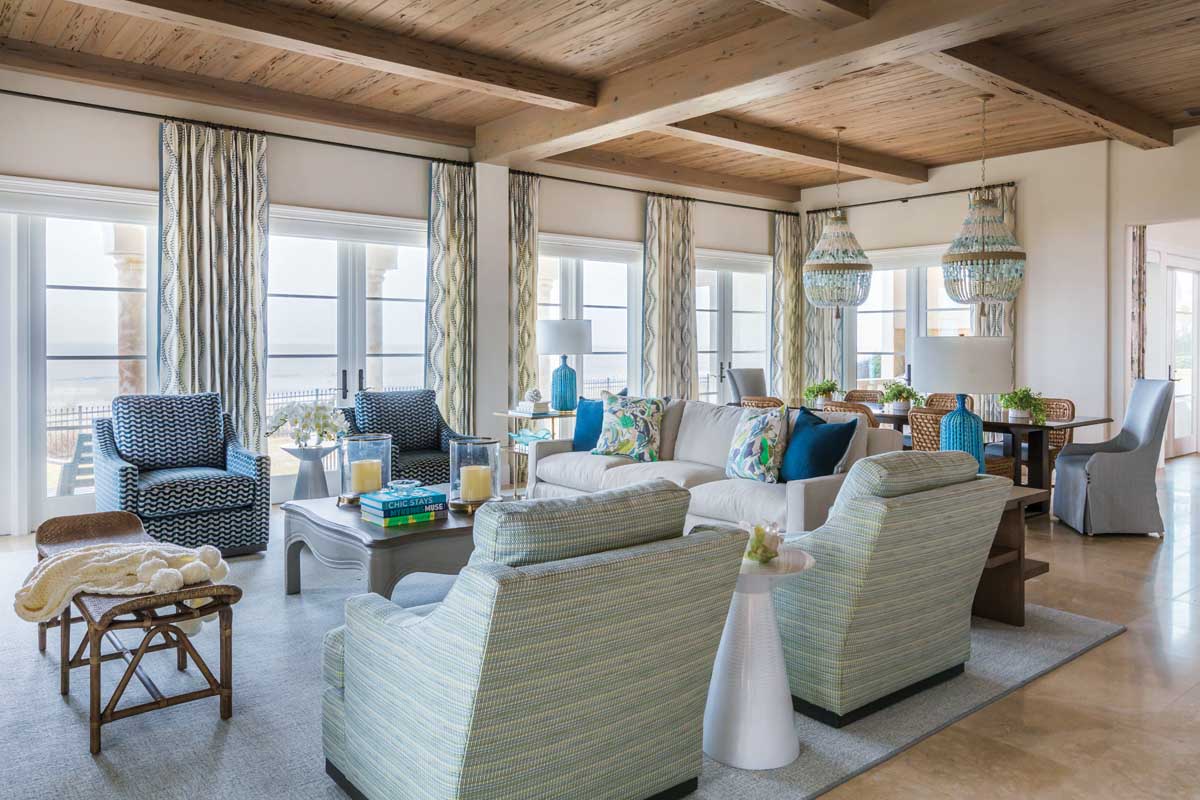 In the family room, all of the chairs swivel to allow for 360-degree views of the ocean outside. The wicker stool in front of the fireplace was chosen to resonate with the breakfast room chairs and to serve as a first stop for children scampering in from a swim.