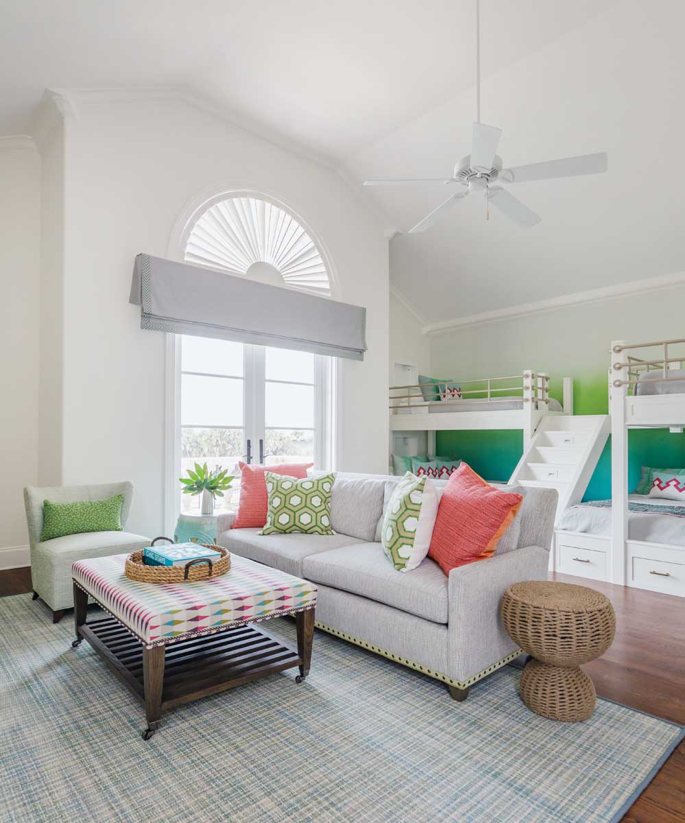 The bunk room was designed as a fun hangout for the homeowners’ grandchildren. The jumping off point for the color palette was the ottoman coffee table. Hannon took a nautical turn with the bunk beds with boat-inspired silver railings. The sofa was chosen with comfort in mind when bedtime reading ends busy days in the sun.