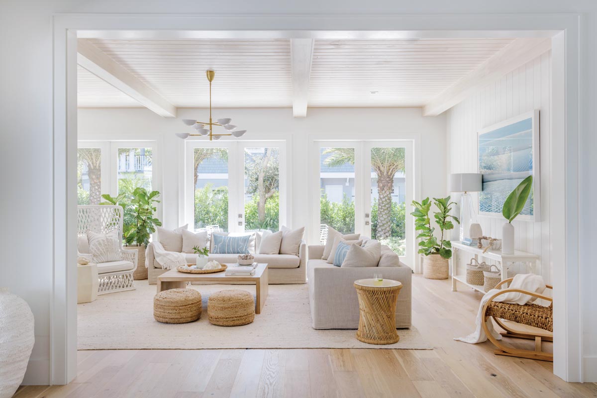 A tide pool photograph by local artist Thomas Hager and soft blue pillows covered in a Lee Jofa fabric add a splash of color to the otherwise neutral living room. Refinished vintage rattan and wicker accents, including a loveseat and console sourced in Palm Beach a decade ago, finally found a home in the center of the space.