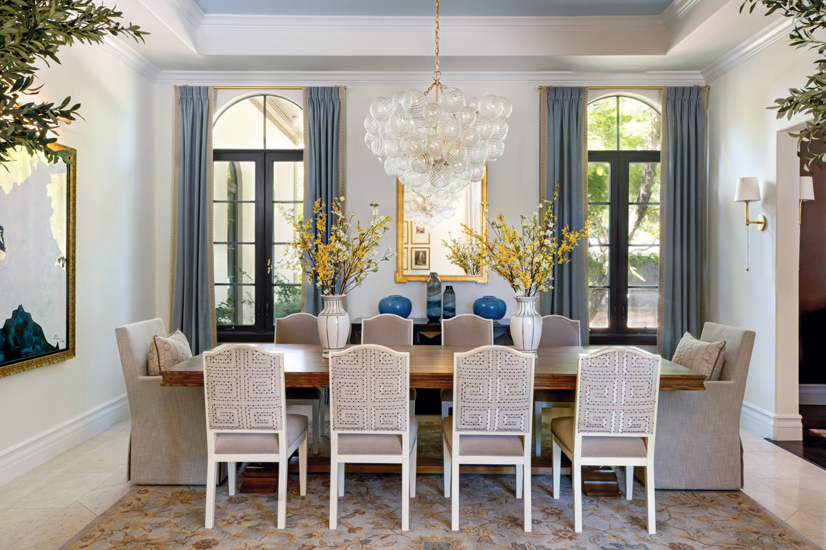 A Chaddock dining room table commands the space with guest chairs from Made Goods and host chairs from RH, all upholstered in Schumacher fabrics. A large blown-glass Julie Neill chandelier from Circa Lighting appears to float in the room.