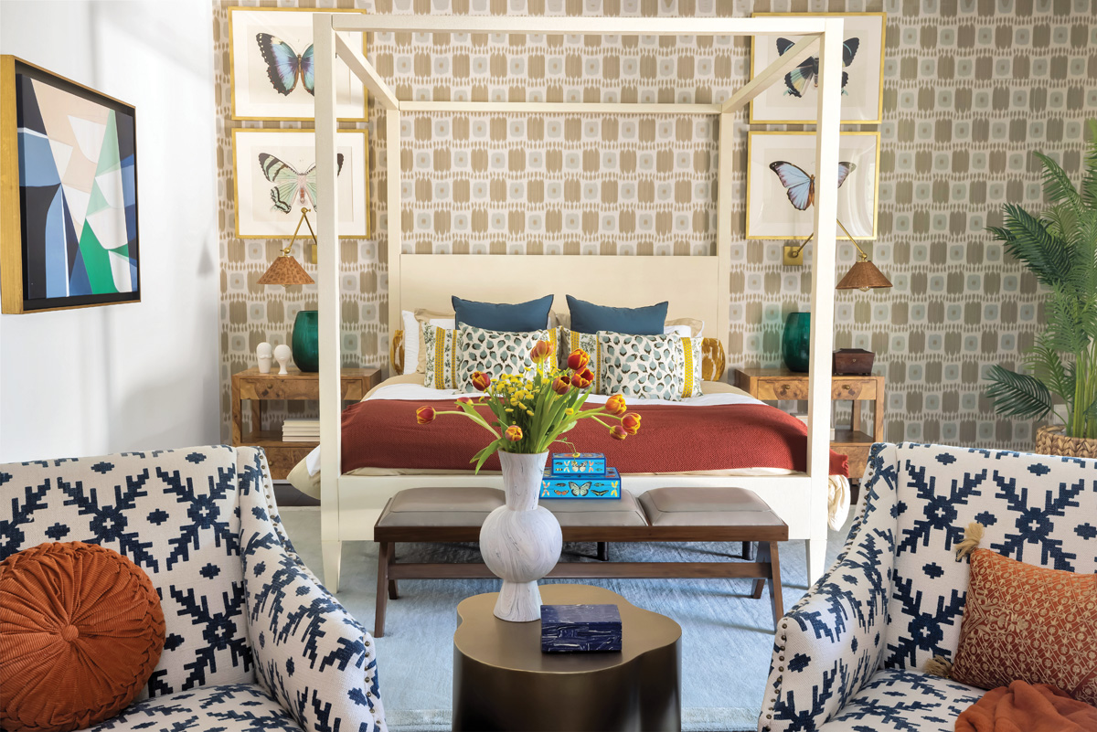Schumacher wallpaper sets the tone in the primary bedroom. Butterfly artwork from Serena & Lily frames a poster bed by Made Goods, and two club chairs from OKA share an Arteriors side table.