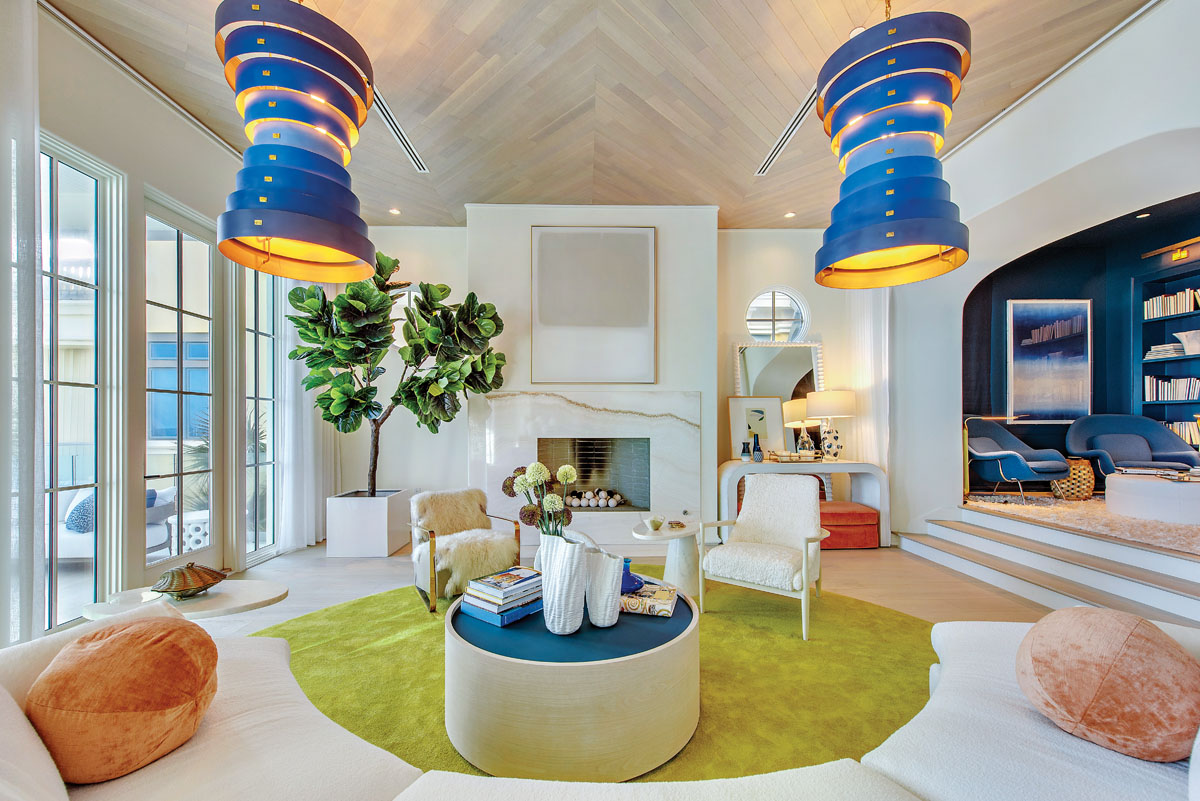 The living room’s ceiling features the same white Belgian oak found in the flooring, accentuated with light fixtures from Currey & Co. The bold citron-hued area rug and sculptural chairs flanking the fireplace infuse an artsy vibe. To the right and up three steps is one of the home’s architectural surprises: a blue-hued library. “It’s like a beautiful cocoon,” says Pamela. “It’s my favorite spot in the house.”