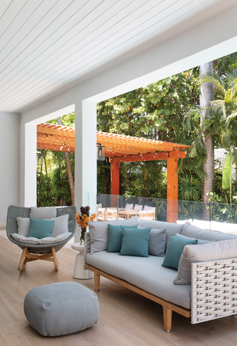 A glassed-in patio with Jean-Marie Massaud’s Sealine sofa and Sebastian Herkner’s Mbrace wicker rocking chair allows the home’s residents to enjoy the outdoors with sun and rain protection.