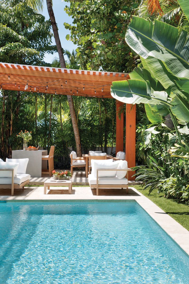 Hedged with native trees and planting​s by landscape designer Patricia Golombek, the outdoor pool deck​ offers a welcoming spot for entertaining​ with tables and seating from Janus et Cie and Clima Home.