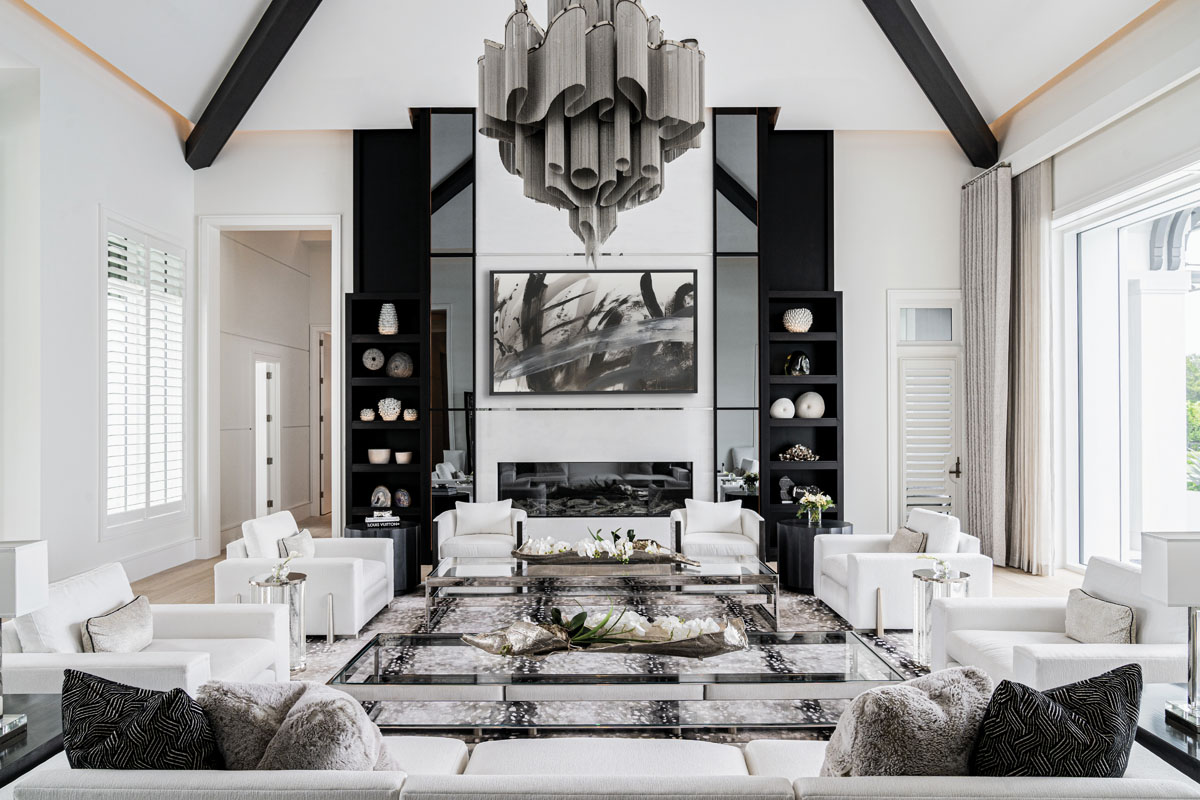 To impart cosmopolitan elegance, the palette in the main living room consists of black, white, and gray. The large chandelier by Terzani drove the design decisions in this part of the home, which features symmetrically paired chairs and a sofa opposite the expanse of the fireplace.
