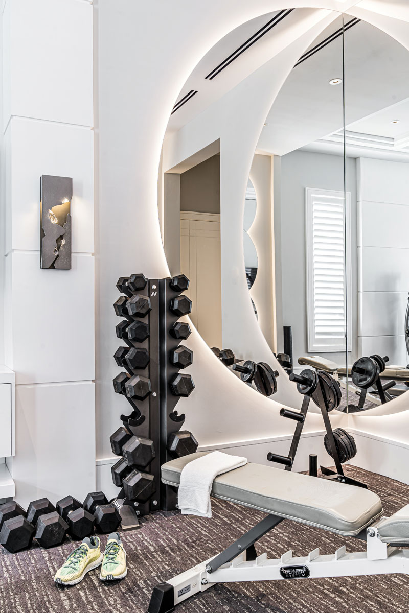 The clients didn’t want a run-of-the-mill weight room, so Midnet’s team installed dramatic circular mirrors with LED lights and multiple sconces to make the space more inviting.