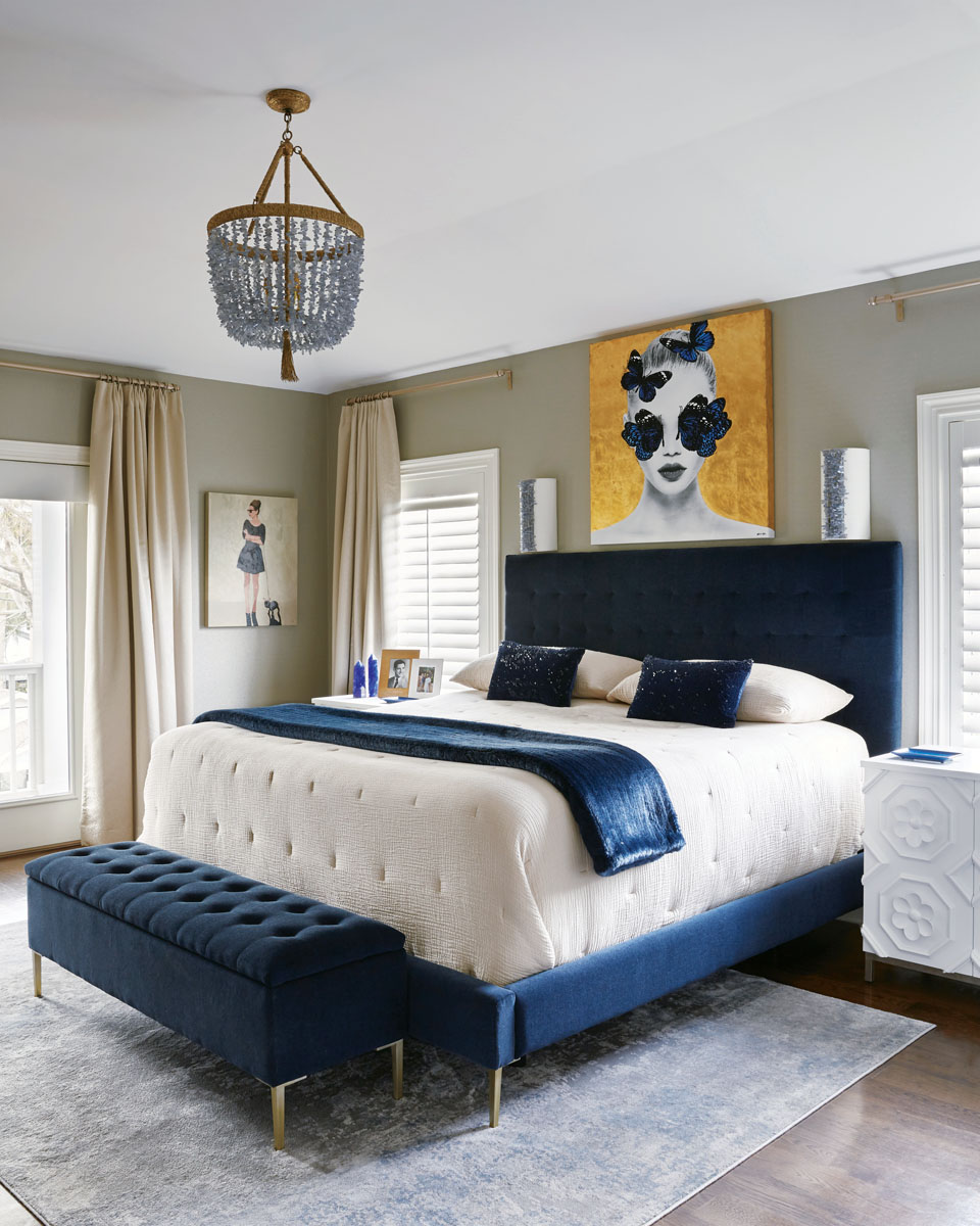 Robyn Branch_FD31-2E Photography by Zeke Ruelas Photography, Nashville, TN In the master bedroom, Branch hung “girly” artwork, thick metallic thread draperies, and a chandelier to create a soothing retreat with a few glittery flourishes. Navy blues and whites offer a grownup touch, while the bench at the foot of the bed helps the client’s dogs reach the bed.