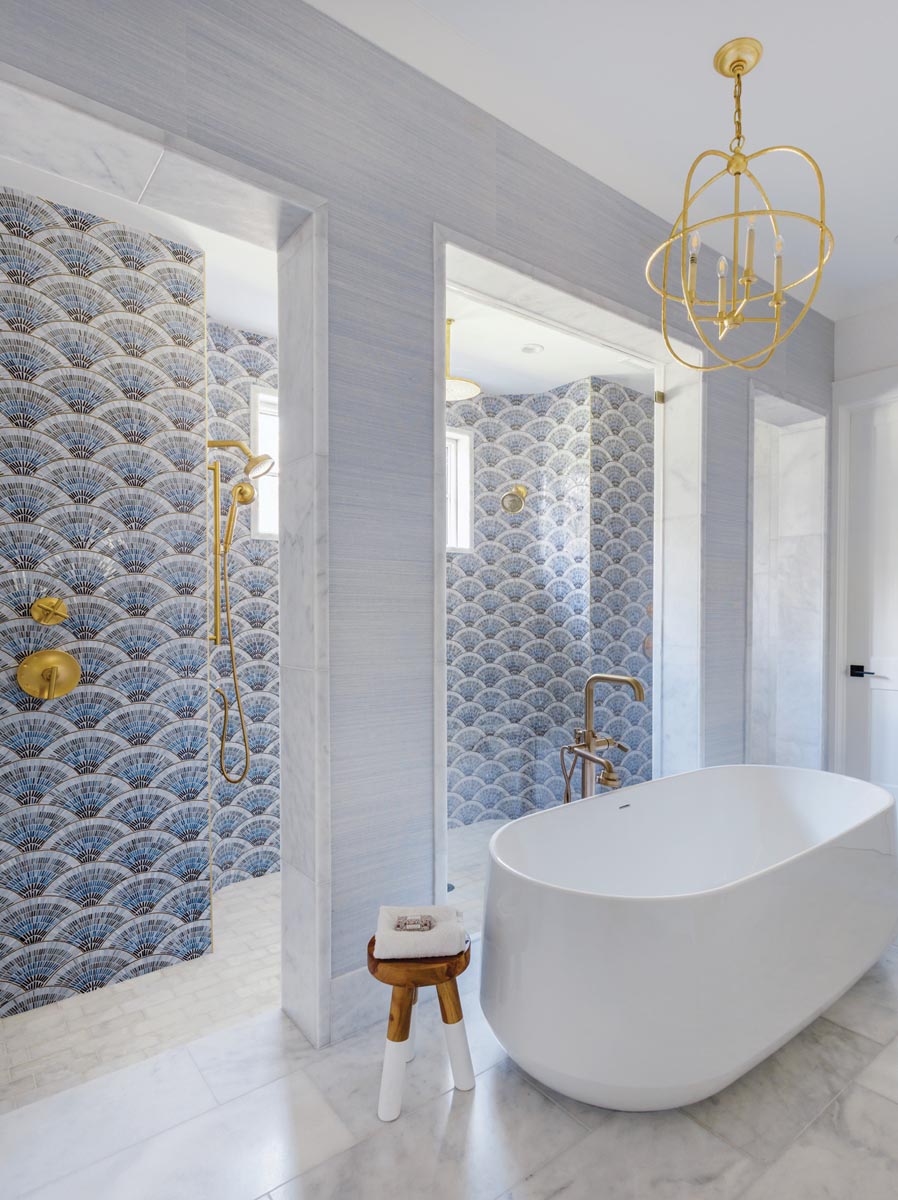 The brass-trimmed blue tile in the primary bath is an all-around favorite. “It’s just a showpiece when you walk into the bathroom,” says Leonard. Her client agrees: “My favorite tilework in the house is the bathroom shower wall,” says Liza. Grasscloth wallpaper maintains the coastal vibe.